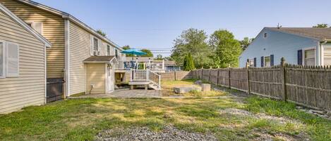 A residential backyard with a wooden deck, a small patio, and a fenced area.