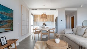 Un salon moderne comprenant un canapé, une table à manger avec des chaises, un coin cuisine et une grande fenêtre.