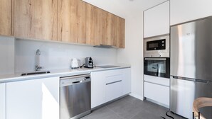 Une cuisine moderne avec des meubles en bois, des appareils en acier inoxydable, un lave-vaisselle et un four encastré.