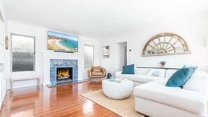 Una sala de estar moderna con chimenea, un sofá, una mesa de centro y un gran ventanal con vistas a la playa.