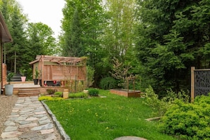 A garden with a wooden structure, stone pathway, and various plants.
