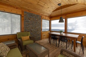 A wooden interior with a dining table, chairs, and a green sofa. - Chalet: Fireplace • Game Room • HotTub • Ski 2min (Les Laurentides Regional County Municipality)
