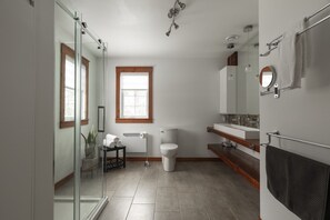 Une salle de bain moderne avec une douche à parois de verre, des toilettes, un lavabo avec un miroir et un porte-serviettes.
