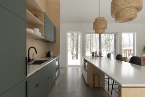 Een moderne keuken met een centraal eiland, inbouwmeubels en grote ramen met uitzicht op het omliggende landschap.
