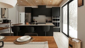 A modern kitchen with black cabinets, a central island, and a large window.
