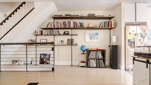Un ampio soggiorno con una scala in legno, scaffali porta libri, un globo e un altoparlante nero.