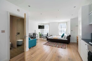 Un appartement moderne doté d’un grand lit, d’un coin repas, d’une télévision et d’une cuisine.