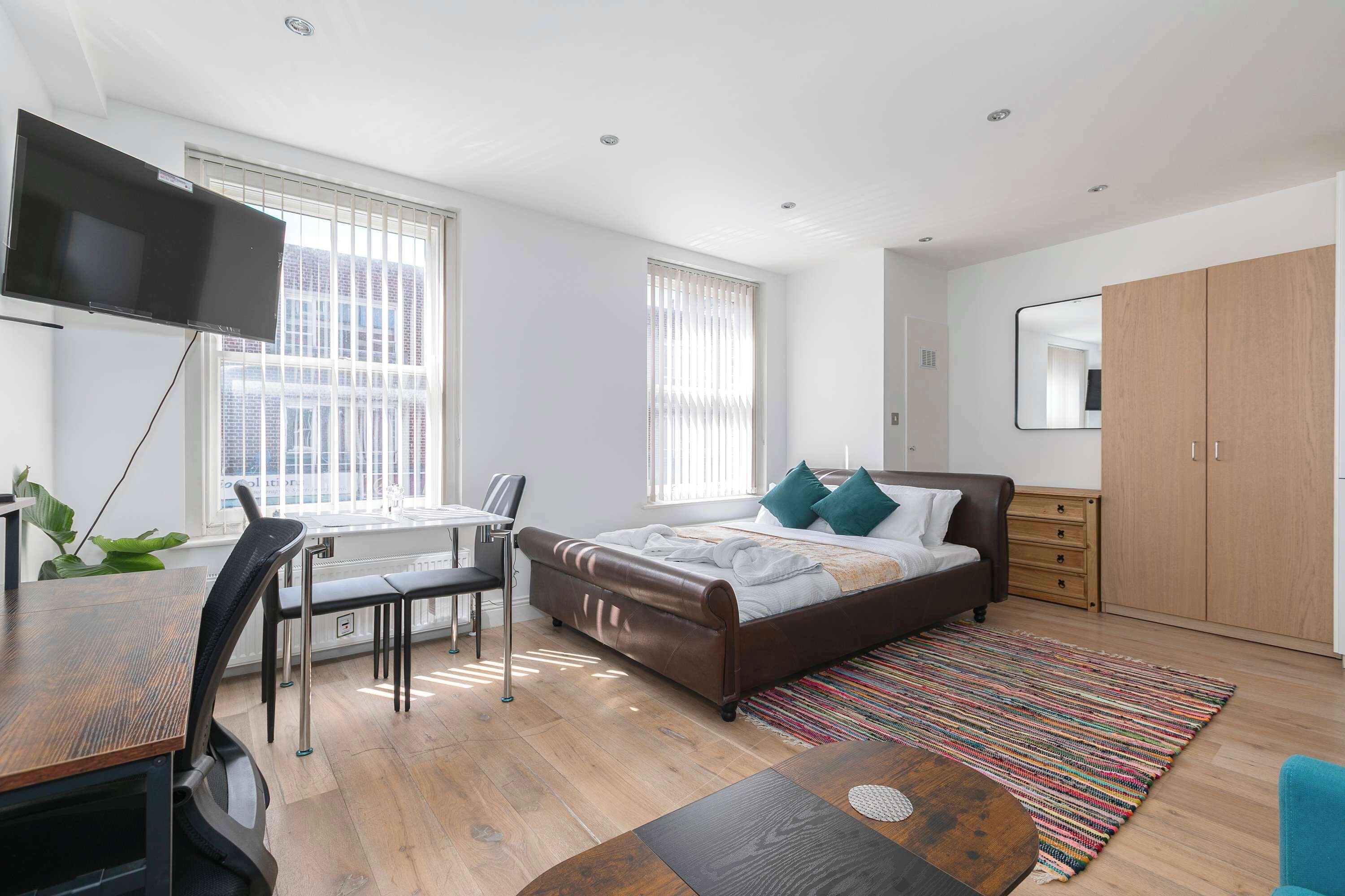 Une chambre moderne comprenant un lit, un bureau, une chaise, un téléviseur et une armoire.