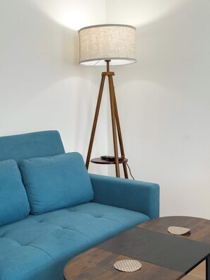 A blue sofa with a small table and a floor lamp in a room.