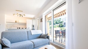 A modern living room with a grey sofa, a wooden coffee table, and a view of a balcony with outdoor furniture. - 4* apartment | swimming pool | parking | wifi (Saint Raphaël)