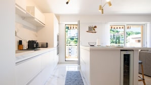 A modern kitchen with white cabinetry, a built-in dishwasher, and a large window offering a view of the outdoors. - 4* apartment | swimming pool | parking | wifi (Saint Raphaël)