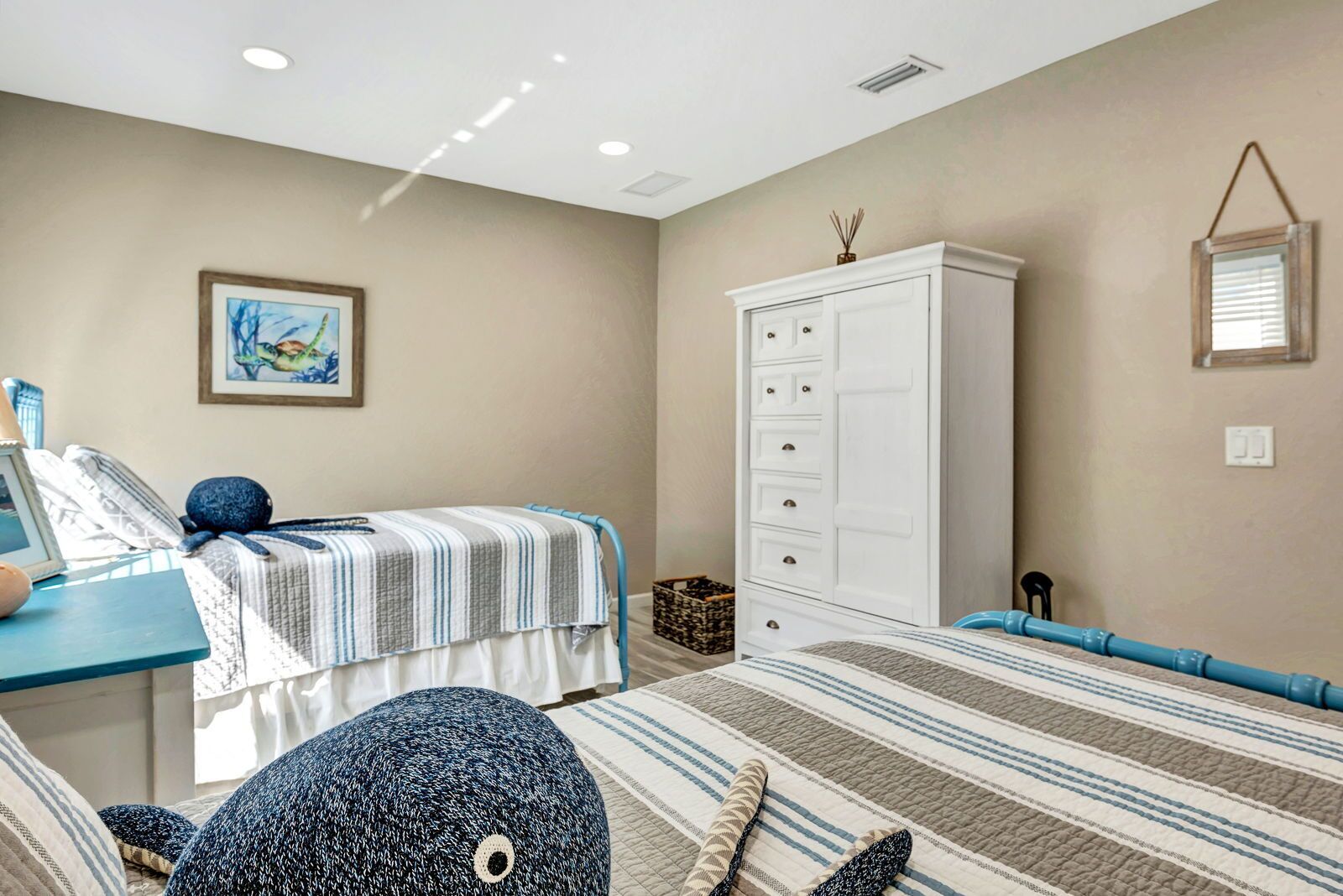 A bedroom with a bed, a desk, a wardrobe, and a framed picture on the wall.