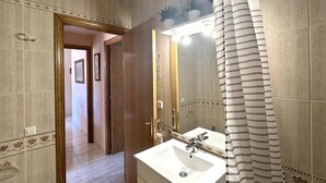 Un baño con lavamanos blanco, espejo y cortina de ducha.
