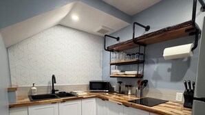 Eine moderne Küche mit weißen Schränken, einer Holz Arbeitsplatte, einem schwarzen Spülbecken und einer eingebauten Mikrowelle.