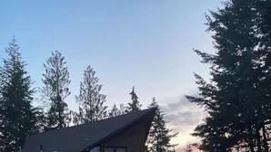 Eine Hütte mit schrägem Dach, einer Veranda und einem Zelt im Vordergrund.