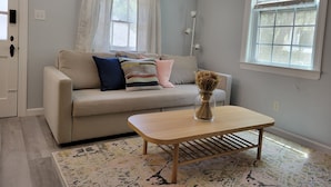 A living room with a beige sofa, a wooden coffee table, and a patterned rug.