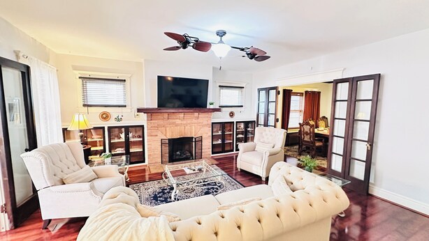A spacious living room with a fireplace, a ceiling fan, and a television. -  Elmwood Village home (Buffalo)