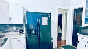 A compact kitchen with white cabinets, a black refrigerator, a coffee maker, and a microwave. -  Elmwood Village home (Buffalo)
