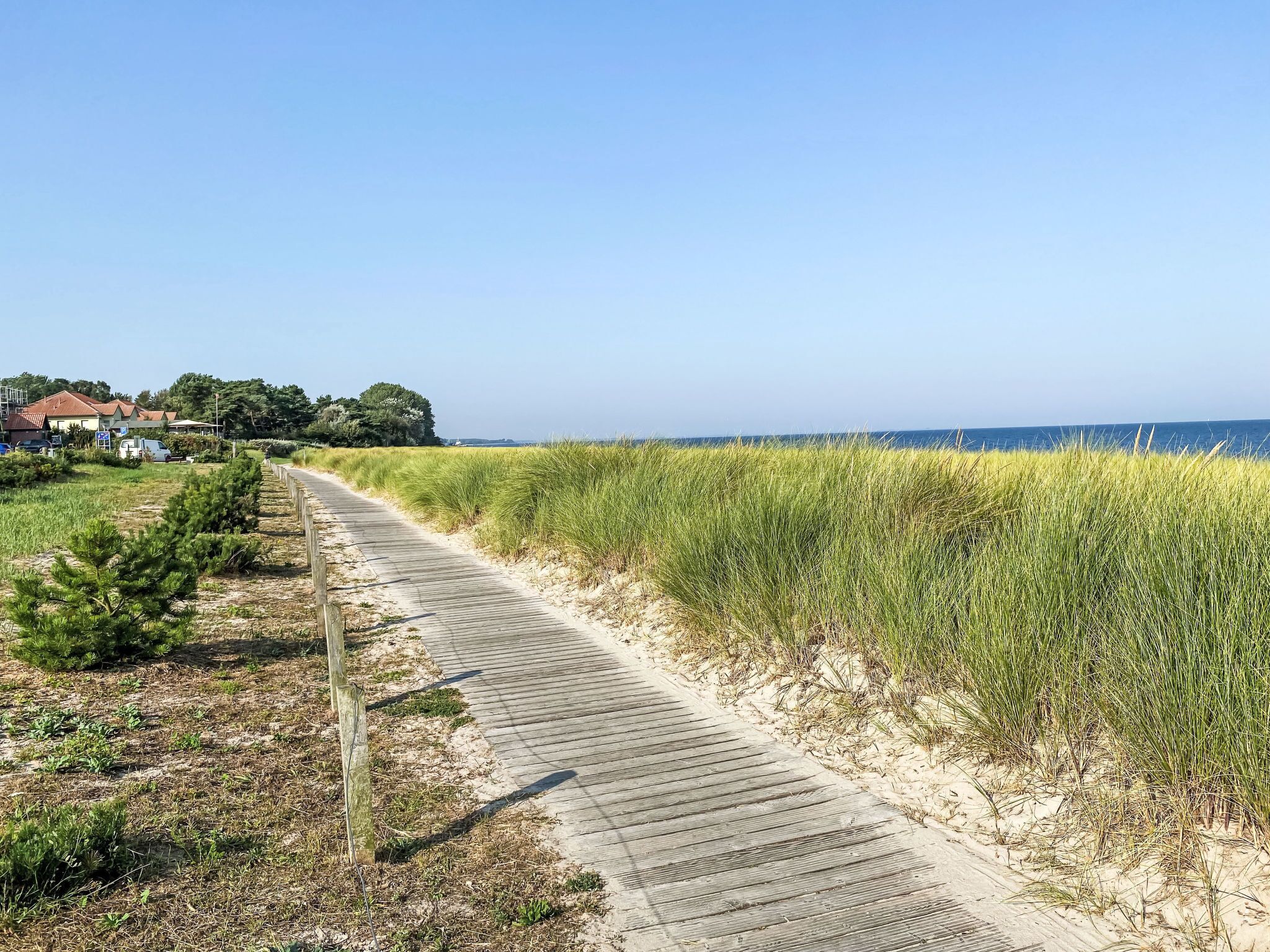 A wooden boardwalk along a beach with a clear view of the ocean.
