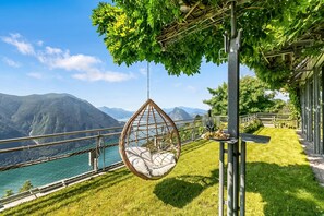 A hanging chair with a view of mountains and a lake.
