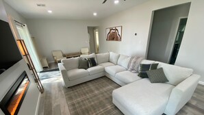 A modern living room with a sectional sofa, a fireplace, and a dining area in the background. - Monkey Island Escape sleeps 8, surrounded by nature with views of Grand Lake. (Monkey Island)