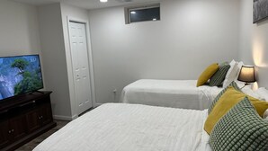 A bedroom with two beds, a television, a dresser, and a wall-mounted TV. - Home away from home with WiFi and AC in delightful Parkville (Parkville)