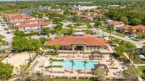 A resort with a central pool, multiple villas, and a landscaped area with palm trees. - Near Disney & Supermarket Amazing Home with Pool (Kissimmee)