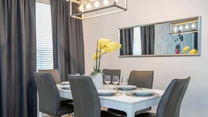 A dining area with a white table, black chairs, a vase with yellow flowers, and a wall-mounted mirror with lights. - Near Disney & Supermarket Amazing Home with Pool (Kissimmee)