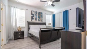 A bedroom with a bed, bedside tables, a ceiling fan, and a TV. - Near Disney & Supermarket Amazing Home with Pool (Kissimmee)