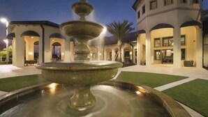 Une fontaine dans une cour, avec un bâtiment en arrière-plan.