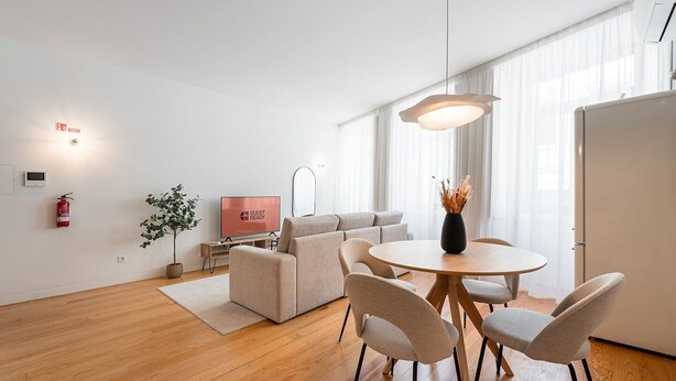 A modern living room with a sofa, a TV, a dining table with chairs, a plant, and a fire extinguisher. - GuestReady - Joy Apartments - C (Porto)