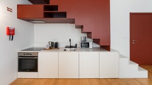 A modern kitchen with a built-in oven, microwave, and sink. There is a red fire alarm on the wall. - GuestReady - Joy Apartments - C (Porto)