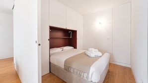 A bedroom with a bed, a wardrobe, and a shower.