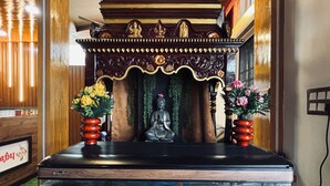 A room with a wooden ceiling, a decorative altar with statues, a fish tank with a mermaid figure, and a reception area with a sign. - HOTEL N N PALACE (Thanjavur)