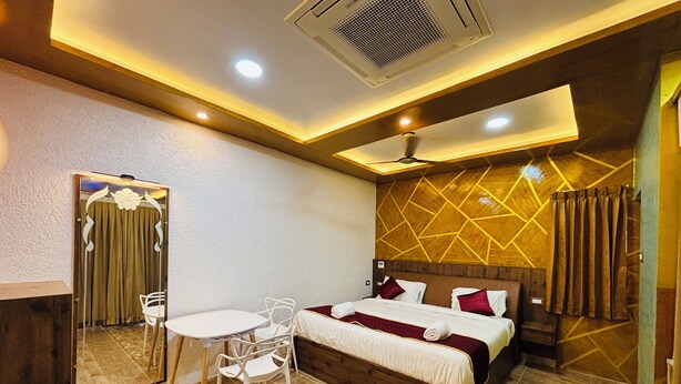 A hotel room with a bed, a desk, a chair, a mirror, and a ceiling fan. - HOTEL N N PALACE (Thanjavur)