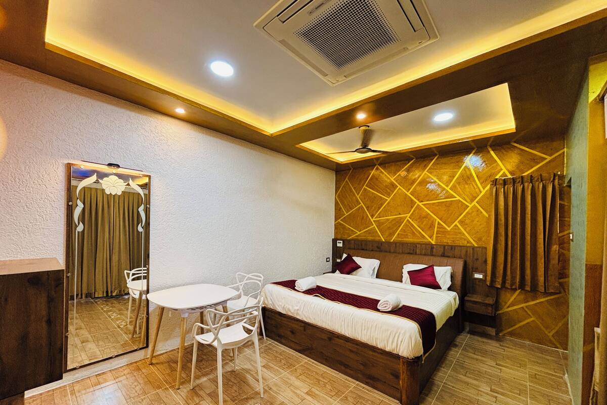 A hotel room with a bed, a desk, a chair, a mirror, and a ceiling fan.