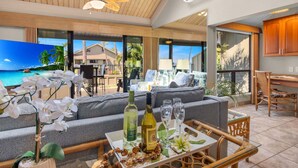 A spacious living area with a large sofa, a coffee table with drinks and snacks, and a view of the ocean.
