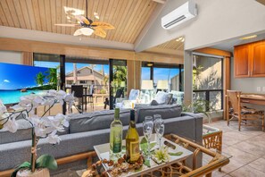 Un amplio salón con un sofá grande, una mesa de centro con bebidas y aperitivos, y vistas al océano.