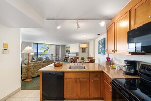 A compact kitchen with wooden cabinets, a dishwasher, a stove, and a coffee maker.