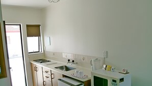Eine kleine Küche mit Spüle, Herd, Mikrowelle und Kühlschrank.