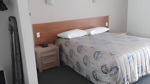 Ein Hotelzimmer mit einem Bett, einem Holz-Kopfteil, einem Nachttisch mit Lampe und einem Kleiderschrank.
