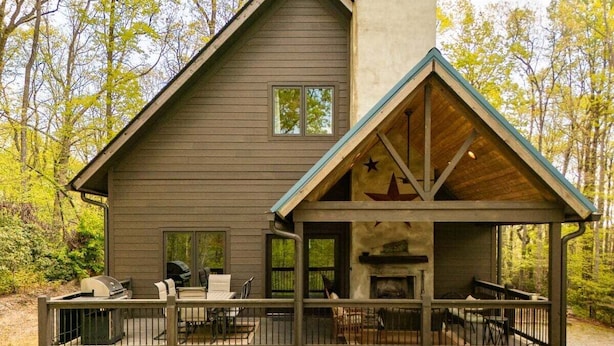 Eine Hütte mit Terrasse, Sitzgelegenheiten im Freien und Kamin.