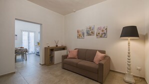 Una sala de estar con un sofá marrón, una mesita auxiliar y tres cuadros florales en la pared.