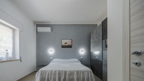 Un dormitorio con cama, dos lámparas de pared, una ventana con cortina y una puerta.