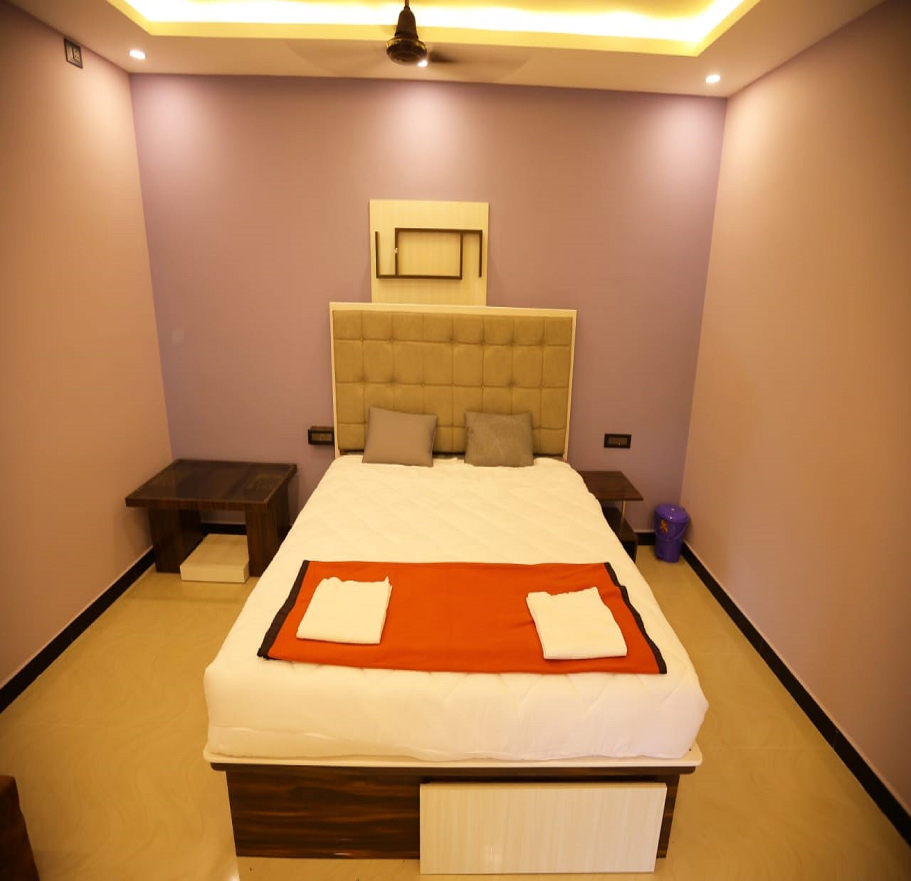 Um quarto bem arrumado com uma cama grande, mesa de cabeceira e luminária no teto.