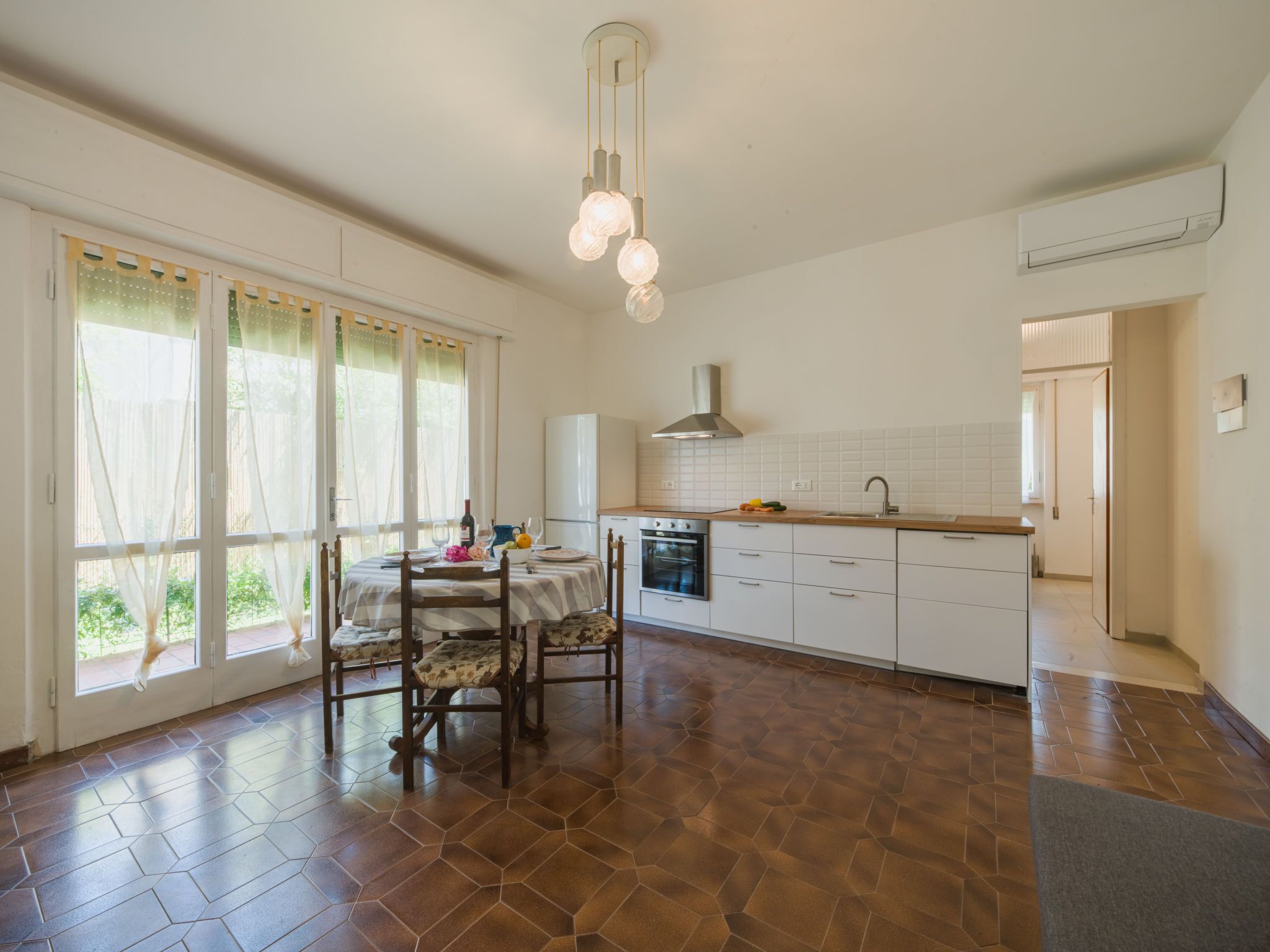 A spacious kitchen with a dining area, large windows, and a modern light fixture.