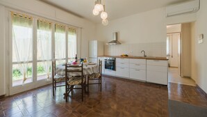 Eine geräumige Küche mit Essbereich, großen Fenstern und einer modernen Leuchte.