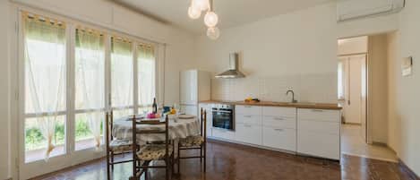 A spacious kitchen with a dining area, large windows, and a modern light fixture.