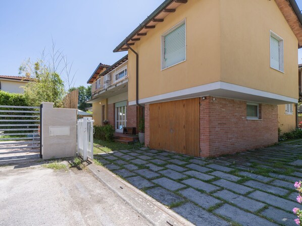 A two-story house with a garage, a gated entrance, and a paved driveway.