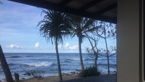 A wooden deck overlooking a beach with palm trees and the ocean. - Dany Island (Turtle Bay)